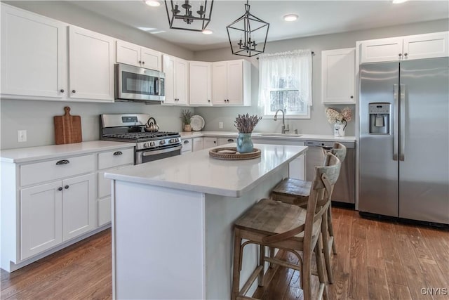 kitchen with a kitchen breakfast bar, wood finished floors, appliances with stainless steel finishes, and a sink