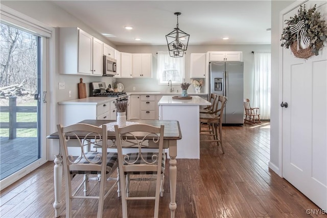 kitchen with stainless steel appliances, light countertops, white cabinets, and dark wood-style floors