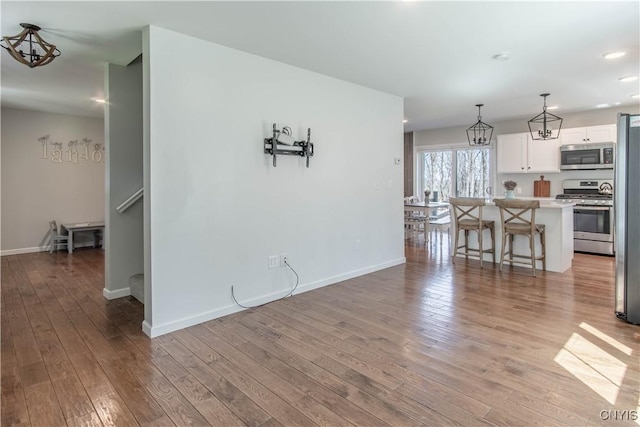 living room with an inviting chandelier, baseboards, and wood-type flooring