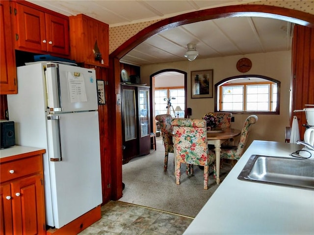 kitchen with arched walkways, freestanding refrigerator, light countertops, a sink, and black microwave