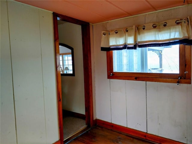 unfurnished room with arched walkways and dark wood finished floors