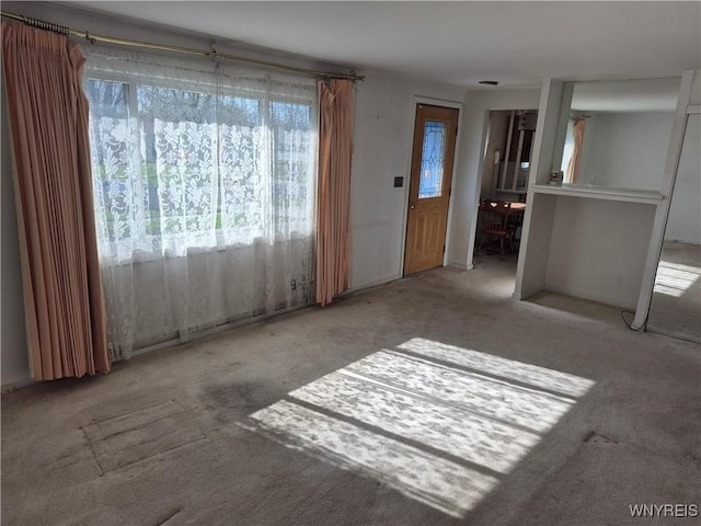 unfurnished living room with baseboards and carpet floors