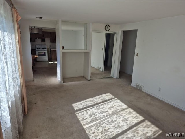 unfurnished bedroom with visible vents, light carpet, and multiple closets