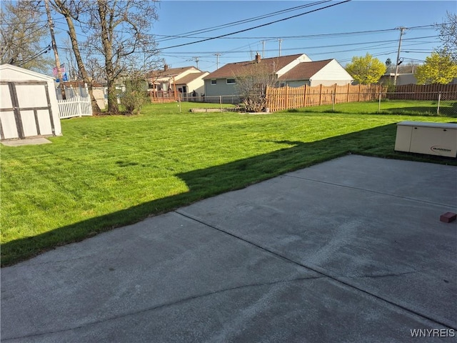 view of yard featuring a patio, fence, an outbuilding, and a storage shed