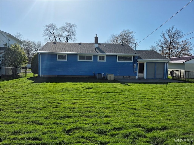 rear view of property featuring fence, cooling unit, a chimney, and a yard