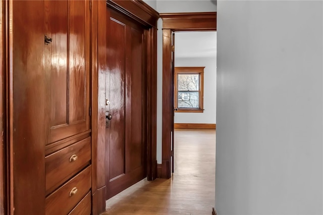 corridor with light wood-style flooring and baseboards