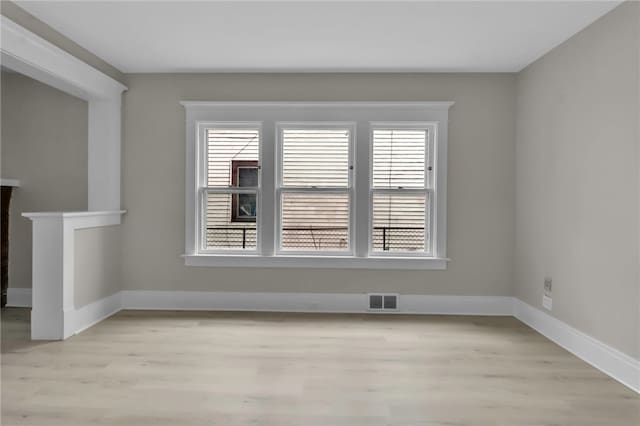 empty room with baseboards, visible vents, and light wood-style floors