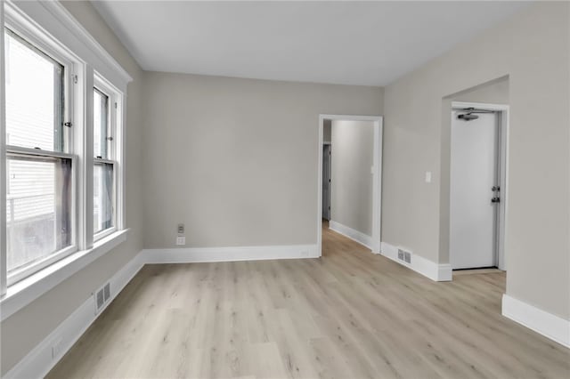 unfurnished room with baseboards, visible vents, light wood finished floors, and plenty of natural light