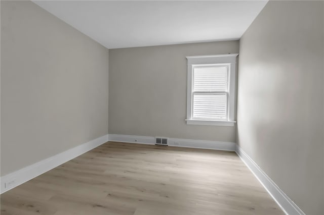 empty room featuring visible vents, light wood-style flooring, and baseboards