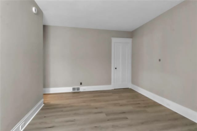 empty room with visible vents, wood finished floors, and baseboards