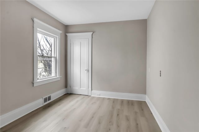 spare room featuring baseboards, visible vents, and light wood-style floors