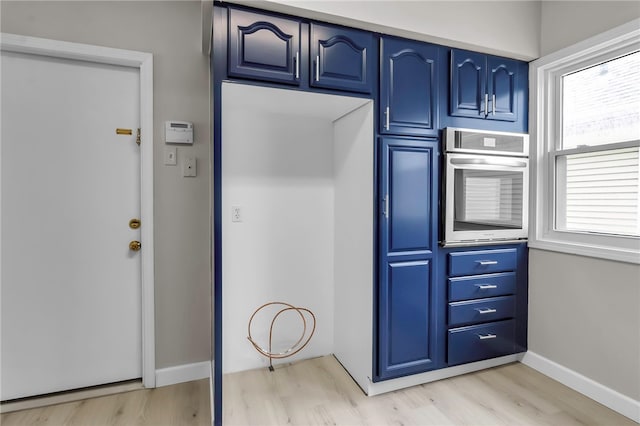 kitchen featuring light wood-type flooring, baseboards, blue cabinetry, and oven