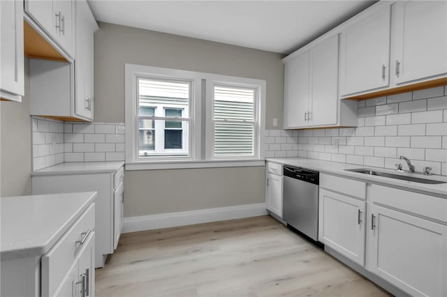 kitchen with a sink, light countertops, light wood-style flooring, baseboards, and dishwasher