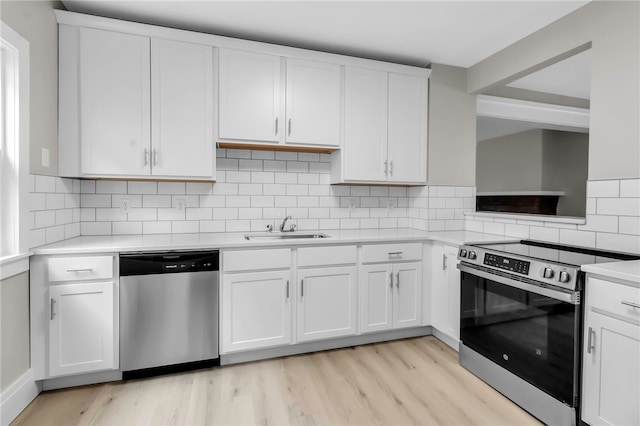 kitchen with white cabinetry, a sink, stainless steel appliances, light countertops, and light wood finished floors