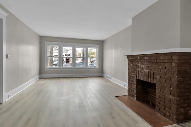 unfurnished living room featuring baseboards, visible vents, wood finished floors, and a fireplace