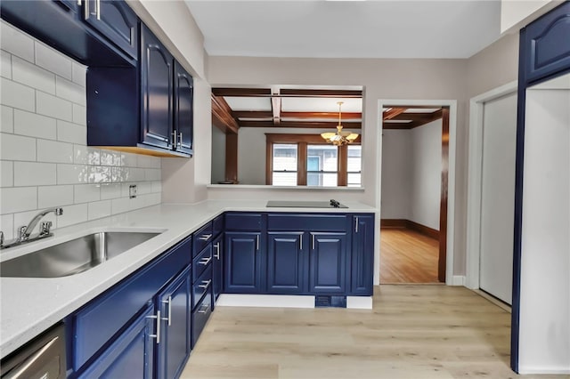 kitchen with light wood-style floors, blue cabinets, a notable chandelier, and a sink