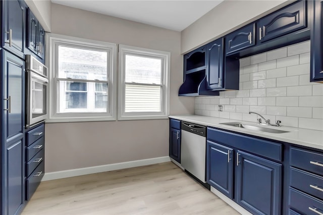 kitchen with a sink, a healthy amount of sunlight, stainless steel appliances, and blue cabinetry