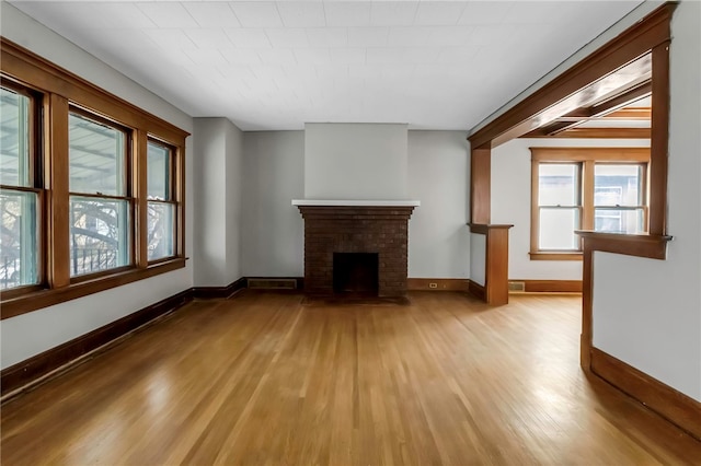 unfurnished living room featuring a wealth of natural light, light wood-type flooring, and baseboards