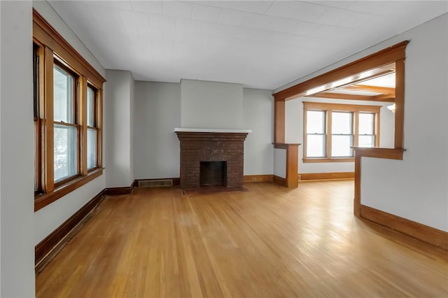 unfurnished living room featuring a brick fireplace, visible vents, light wood-style flooring, and baseboards