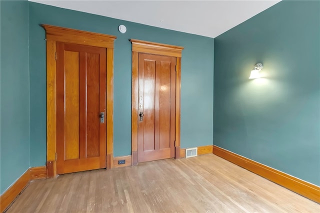 unfurnished bedroom with wood finished floors, visible vents, and baseboards