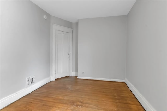 empty room with visible vents, light wood finished floors, and baseboards