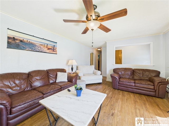 living room with baseboards, light wood-style flooring, ceiling fan, and crown molding