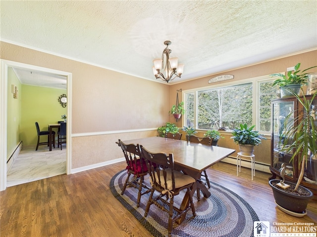 dining room featuring wood finished floors, a baseboard heating unit, a textured ceiling, and a notable chandelier