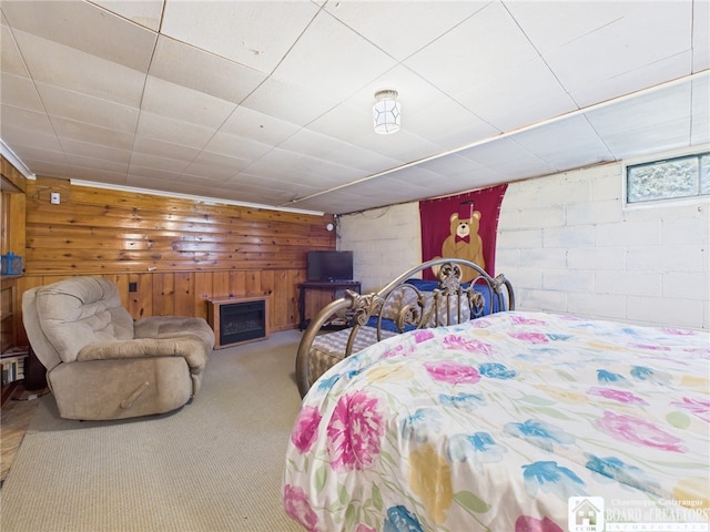 carpeted bedroom featuring wooden walls and concrete block wall