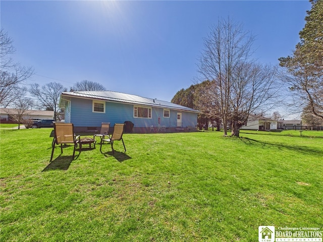 back of property with metal roof and a lawn