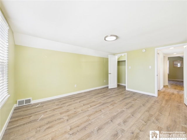 unfurnished room with visible vents, light wood finished floors, and baseboards