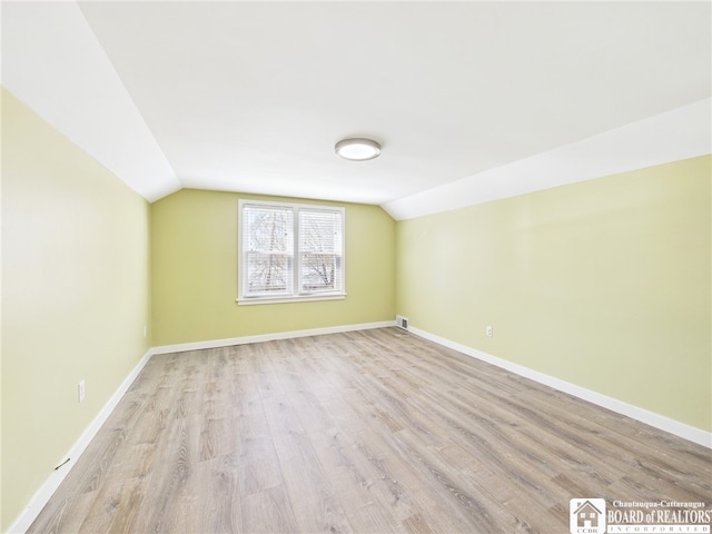 bonus room featuring visible vents, light wood finished floors, vaulted ceiling, and baseboards