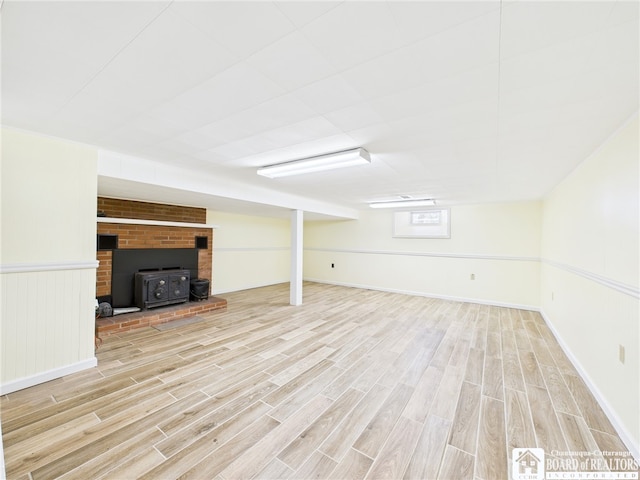 below grade area with a wood stove and light wood-type flooring