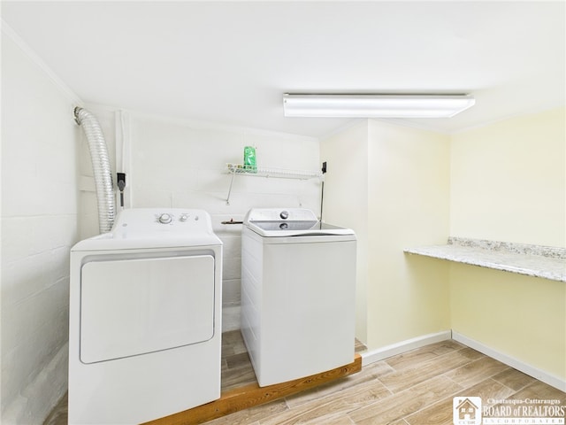 clothes washing area with independent washer and dryer, laundry area, crown molding, baseboards, and wood finished floors