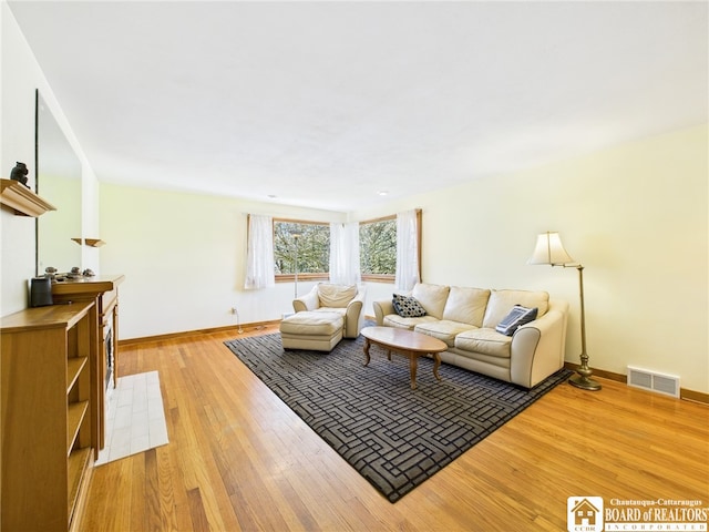 living area with baseboards, visible vents, and light wood-type flooring
