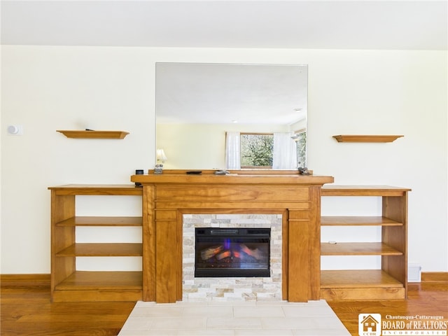 living area with a tile fireplace, wood finished floors, and baseboards