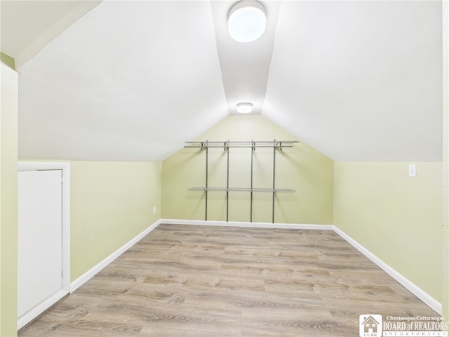 additional living space featuring baseboards, wood finished floors, and lofted ceiling