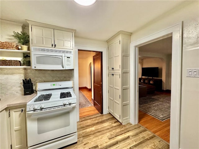 kitchen featuring tasteful backsplash, white appliances, light wood-style floors, light countertops, and white cabinetry