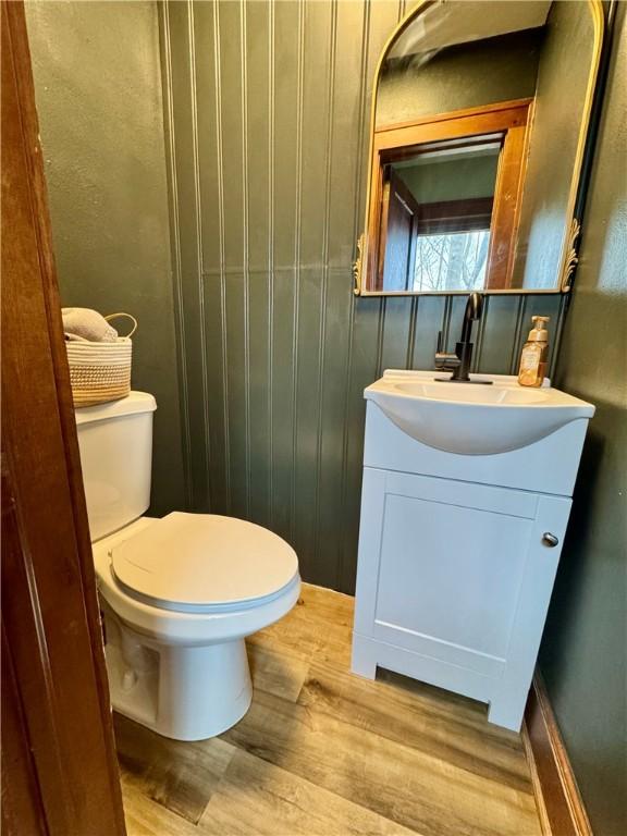 bathroom with wood finished floors, toilet, and vanity