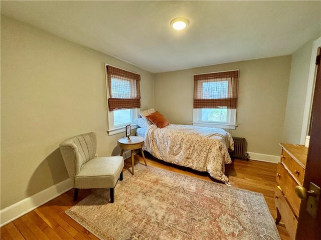 bedroom with radiator heating unit, wood finished floors, and baseboards