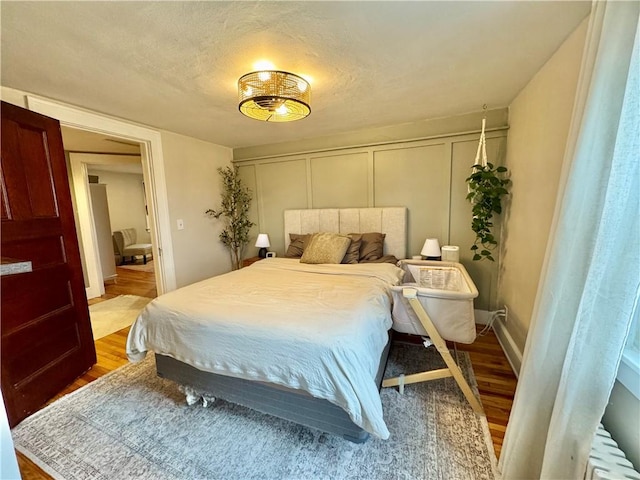 bedroom with wood finished floors and a decorative wall