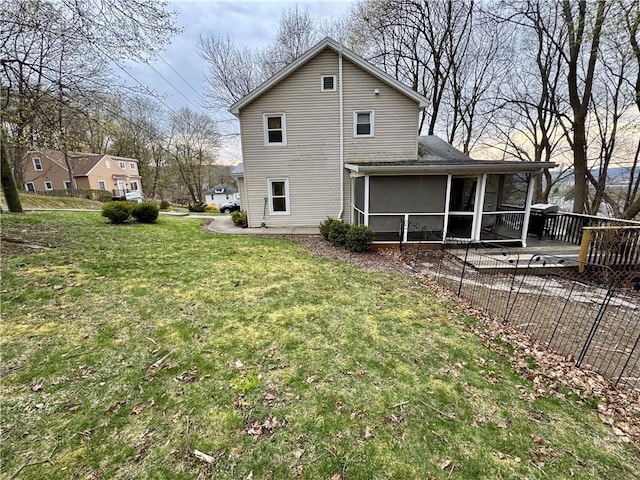 rear view of house with a sunroom, a yard, and fence