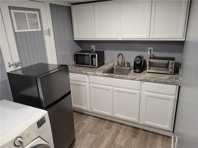 kitchen featuring a sink, light wood-style floors, stainless steel microwave, washer / dryer, and a toaster