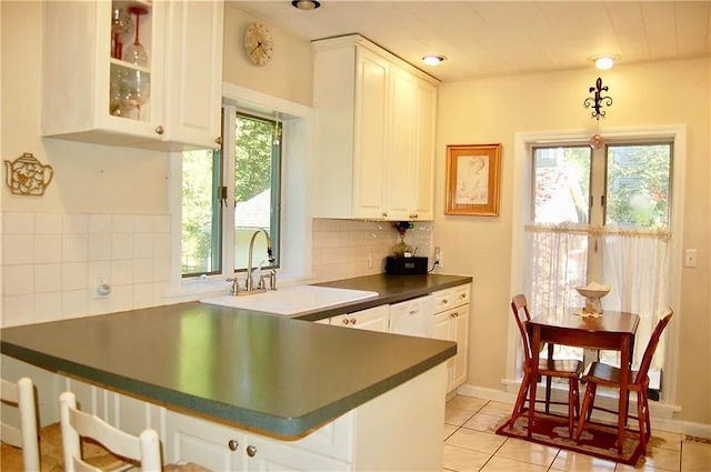 kitchen featuring light tile patterned floors, a healthy amount of sunlight, a sink, and tasteful backsplash