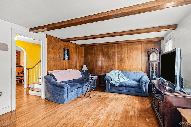 living area featuring arched walkways, beam ceiling, and wood finished floors