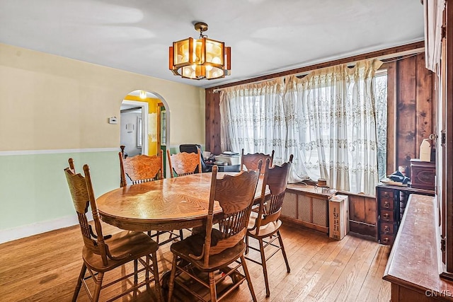 dining room with baseboards, arched walkways, a notable chandelier, and light wood finished floors