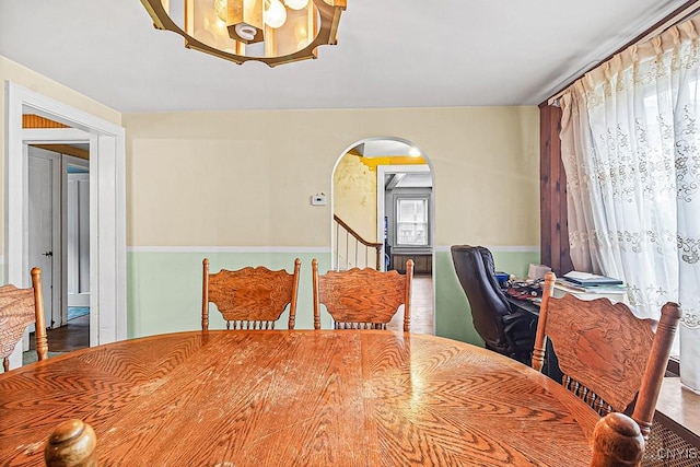 dining space featuring a chandelier, arched walkways, and stairs
