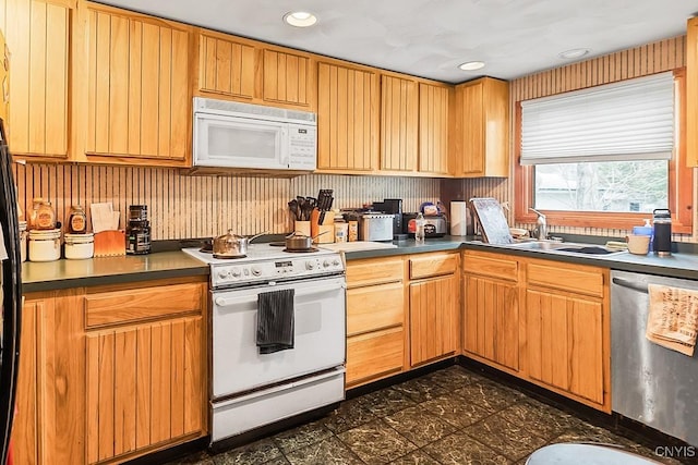 kitchen featuring dark countertops, recessed lighting, a sink, and white appliances