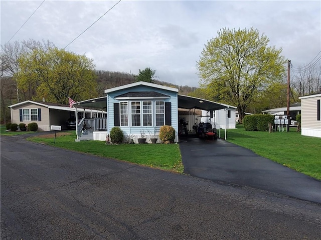 manufactured / mobile home with a front yard, driveway, and an attached carport