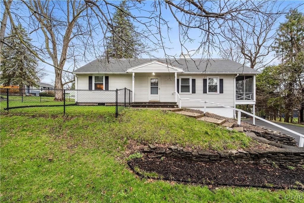 view of front facade featuring fence, a front yard, and a sunroom