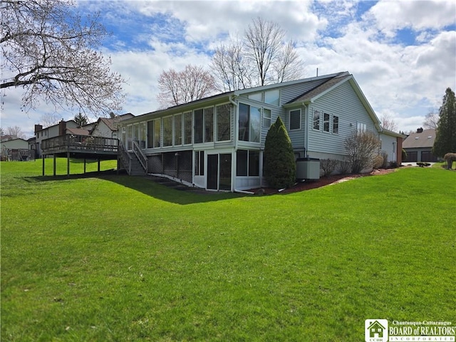 back of house featuring a sunroom, a wooden deck, a yard, and stairway
